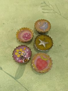 four bottle caps with different designs on them sitting on the ground next to each other