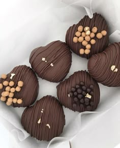 four heart shaped chocolates with nuts on top in a white paper wrapper, ready to be eaten