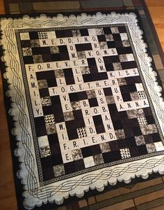 a black and white quilt with words written in it on a wooden floor next to a table