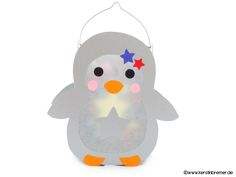 a little penguin with stars on its head and eyes is hanging from a string ornament