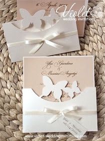 two wedding cards with white butterflies on the front and back, sitting on a wicker basket