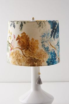 a white lamp with a blue and yellow shade on it's side, sitting on a table