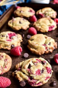 raspberry chocolate chip cookies on a baking sheet with fresh raspberries and chocolate chips