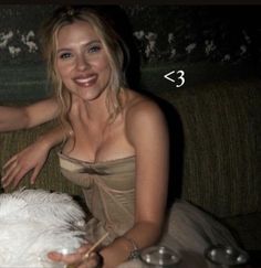 a woman sitting on top of a couch next to a white dog with its tongue out