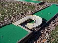 a miniature golf course with a hole in the middle and one hole on the other side