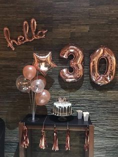 a table topped with balloons and cake next to a sign that says hello 30th on it