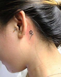 a woman's ear with a small flower tattoo on it