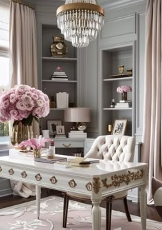 a white desk topped with pink flowers and a chandelier