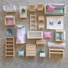 a collection of dollhouse furniture and accessories laid out on the floor in front of a wall