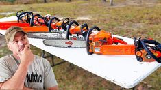 a man is talking on his cell phone next to chainsaws that are sitting on a table