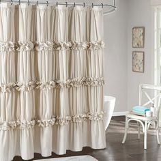 a white shower curtain with ruffles on it in a bathroom next to a chair