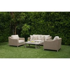 an outdoor living room with grass and trees in the back ground, including couches and coffee table