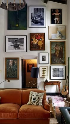 a living room filled with lots of pictures on the wall and furniture in front of it