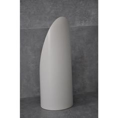 a large white vase sitting on top of a cement floor next to a gray wall