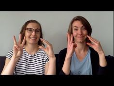 two women sitting next to each other with their hands in the air