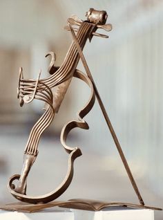 a metal sculpture of a man playing the violin on top of a white book holder