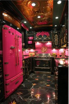 a pink refrigerator in a black kitchen with gold trimmings on the walls and ceiling