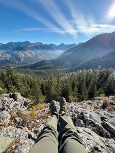 someone is sitting on the edge of a mountain with their feet up in the air