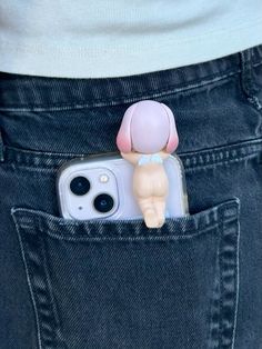 an iphone case with a baby doll sticking out of it's pocket in someone's jeans