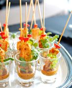 small cups filled with appetizers on top of a silver platter topped with green leafy garnishes