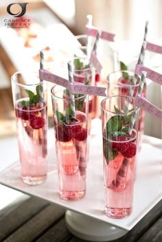 several glasses with strawberries and mints in them on a white tray, ready to be served