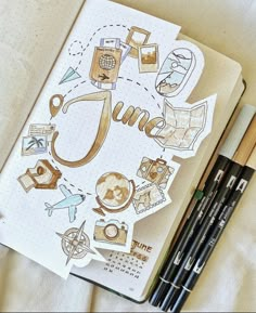 an open notebook with the word june surrounded by doodles and pencils on a bed