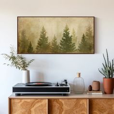 a record player sitting on top of a wooden cabinet next to potted plants and a painting