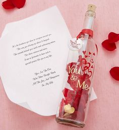 a message in a bottle with hearts on it next to some paper and red rose petals