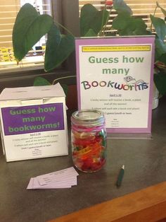 a jar filled with gummy bears sitting on top of a counter next to a sign