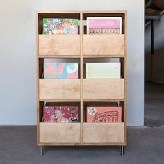 a book shelf with many books on top of it and some papers in the bottom drawer