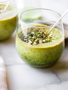 two glasses filled with green smoothie on top of a table