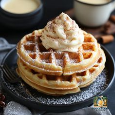 a stack of waffles topped with whipped cream and cinnamon on a black plate