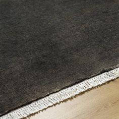 an area rug with fringes on top of it and wood flooring in the background