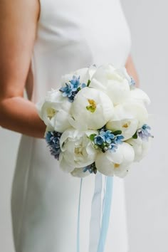 a bride holding a bouquet of white and blue flowers