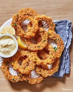 fried onion rings on a plate with dipping sauce and lemon wedges next to it