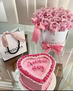 a heart shaped cake sitting on top of a table next to a bouquet of roses