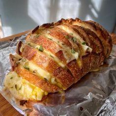 an omelet sandwich is sitting on aluminum foil and sits on a wooden table