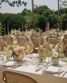 an outdoor table set up for a wedding reception with flowers in vases and place settings