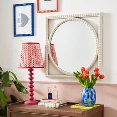 a table with a lamp, mirror and vase on it