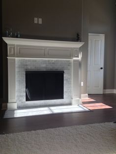 an empty living room with a fireplace and white carpet