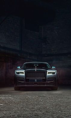 the front end of a rolls royce parked in a dark garage