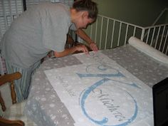 a woman is decorating a bed in her room with blue and white designs on it