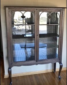 an old china cabinet with glass doors and wood floors