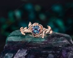 a gold ring with a blue stone in the center on top of a green rock