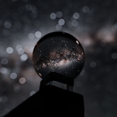 a snow globe sitting on top of a metal pole in front of a night sky filled with stars