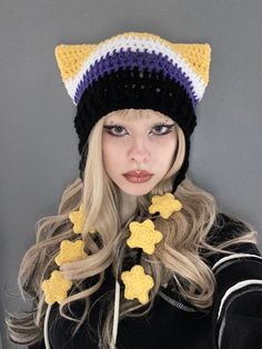 a woman with long blonde hair wearing a knitted hat and yellow flowers on it