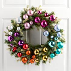 a christmas wreath with ornaments hanging on the front door