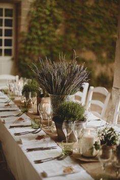 a long table set with place settings and flowers