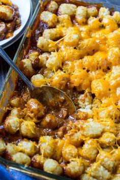 a casserole dish with tater tots in it and a serving spoon