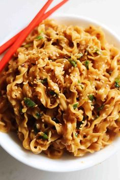 a bowl filled with noodles and chopsticks on top of a table